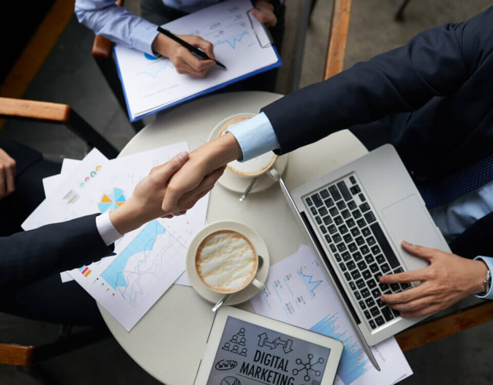 business people shaking hands overtable with documents